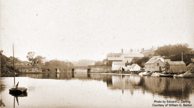 William J. Barton Wrote, "This is Water Street from Summer to Green Street, Ipswich, Mass. For a long time it was called "Clam Shell Alley." The old wooden bridge in the distance was condemned, and a new stone arch bridge was built in 1894. For several years, I have been the last living man who worked on the bridge (not for pay). I helped my father as a boy working on wooden arches that held the granite in place. The Ipswich County House (House of Correction) is at the extreme right of the picture. My father, William E. Barton, had a Massachusetts Bay pilot license, and he piloted the rock sloop loaded with granite to build the new stone arch bridge. The river is not to deep." Photo by Edward L. Darling. Photo by Edward K, Darling.